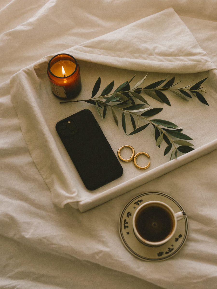 A morning tray with a candle, gold earrings, an olive branch and coffee